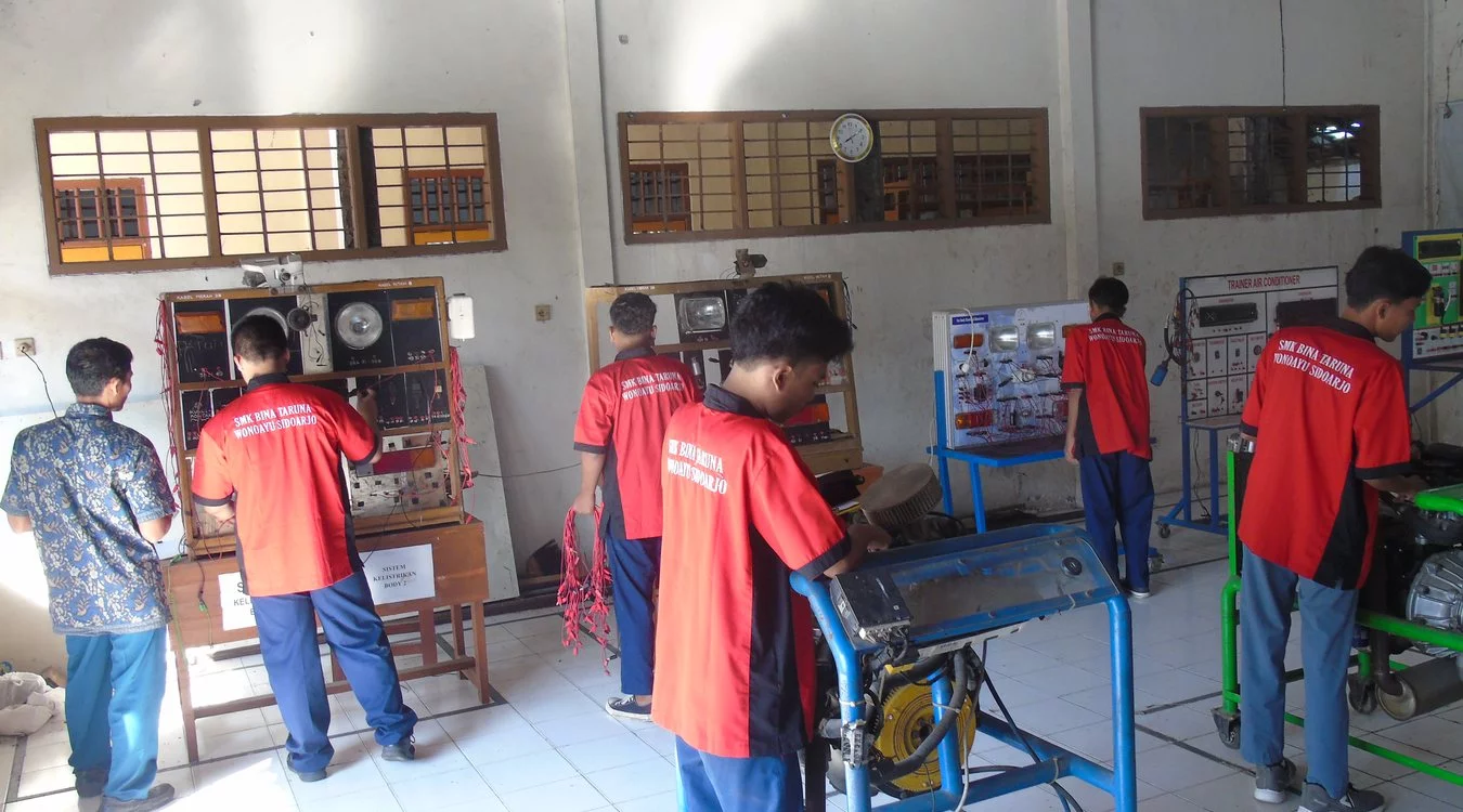 Praktik dengan trainer di bengkel otomotif sekolah