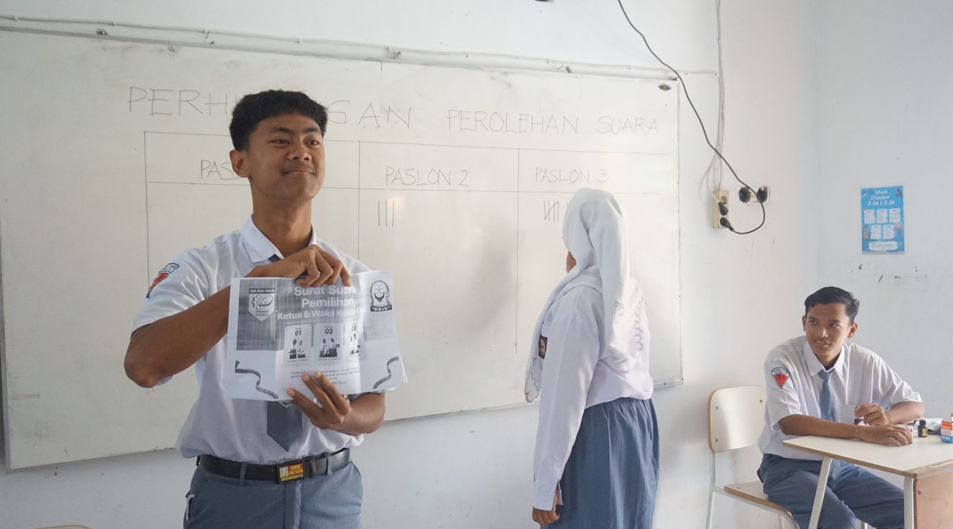 Siswa menunjukkan surat suara sebelum dimasukkan ke kotak suara